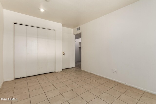 unfurnished bedroom with light tile patterned floors and a closet