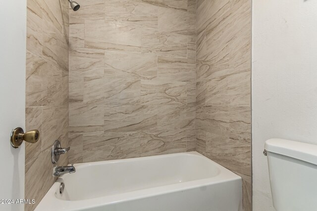 bathroom with toilet and tiled shower / bath combo