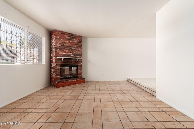 unfurnished living room featuring a brick fireplace and light tile patterned flooring