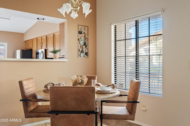 dining room with a notable chandelier and vaulted ceiling