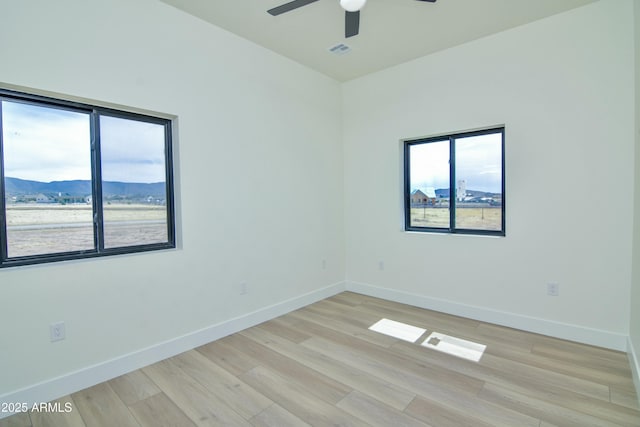 spare room with baseboards, ceiling fan, visible vents, and light wood finished floors
