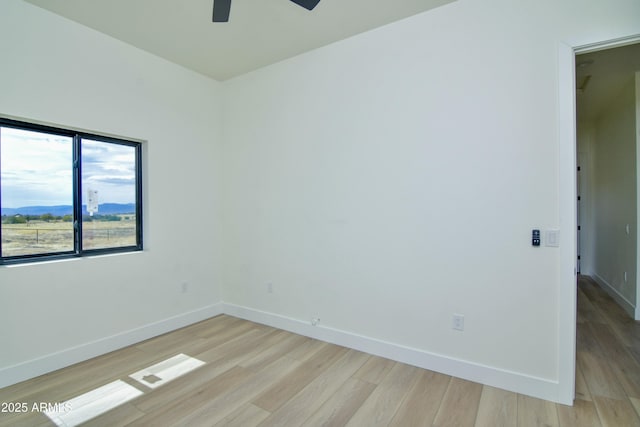 spare room with a ceiling fan, baseboards, and light wood-style floors