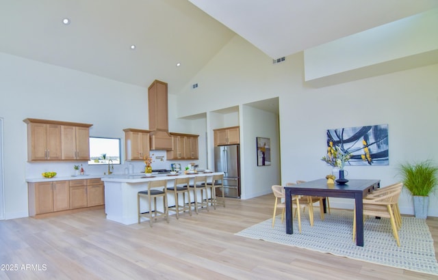 kitchen featuring freestanding refrigerator, light countertops, a kitchen bar, and light wood-style flooring