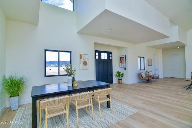 dining area with baseboards, a towering ceiling, and light wood finished floors