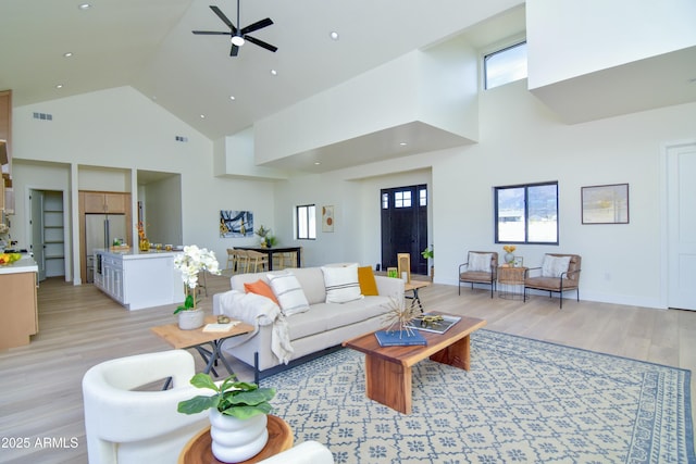 living area featuring light wood finished floors, visible vents, high vaulted ceiling, and ceiling fan