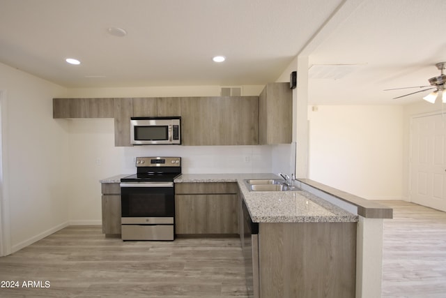 kitchen with sink, light wood-type flooring, appliances with stainless steel finishes, ceiling fan, and light stone countertops