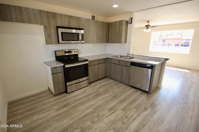 kitchen with sink, appliances with stainless steel finishes, kitchen peninsula, ceiling fan, and light hardwood / wood-style floors