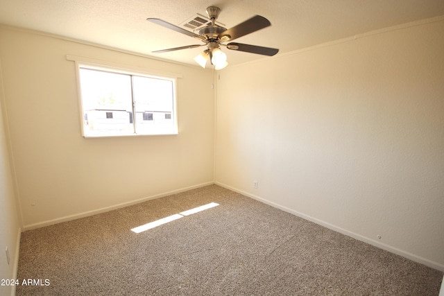 empty room with ornamental molding, ceiling fan, and carpet flooring