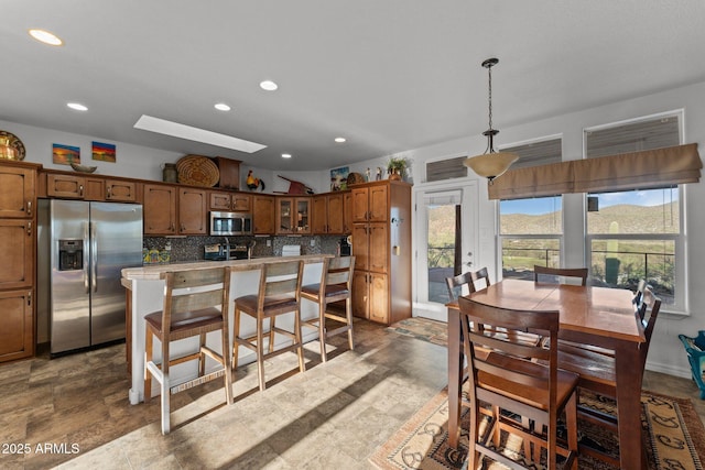3874 Pura Vida Trl, Wickenburg, AZ 85390 - kitchen with a kitchen island, appliances with stainless steel finishes, brown cabinets, and decorative backsplash