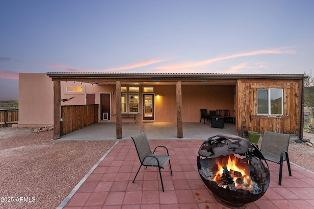 3874 Pura Vida Trl, Wickenburg, AZ 85390 - back of house at dusk featuring a fire pit, stucco siding, and a patio