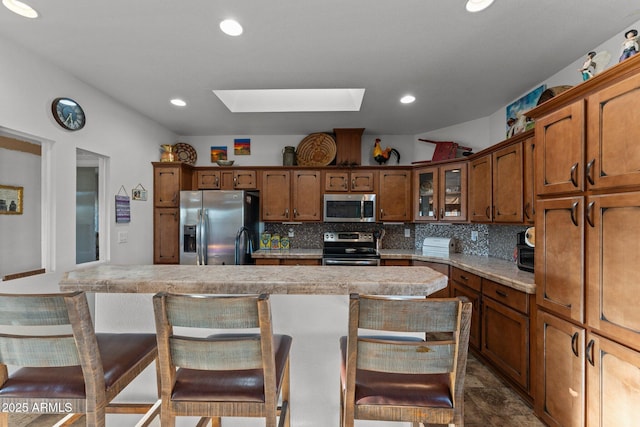 3874 Pura Vida Trl, Wickenburg, AZ 85390 - kitchen featuring light countertops, tasteful backsplash, a kitchen breakfast bar, a skylight, and stainless steel appliances