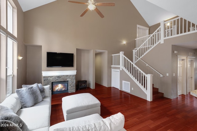 living room with high vaulted ceiling, ceiling fan, a stone fireplace, and hardwood / wood-style floors