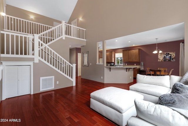 living room with an inviting chandelier, a towering ceiling, and dark wood-type flooring