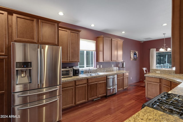 kitchen with pendant lighting, a notable chandelier, sink, stainless steel appliances, and dark hardwood / wood-style floors