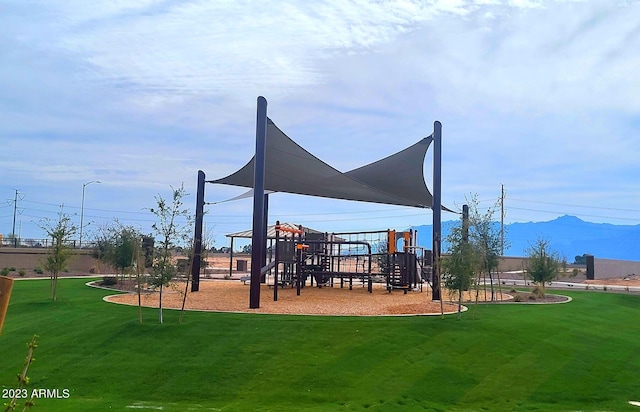 view of jungle gym featuring a lawn and a mountain view