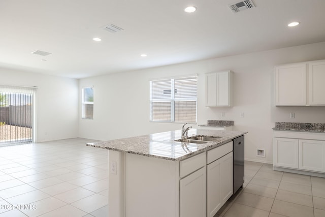 kitchen with light stone countertops, stainless steel dishwasher, sink, white cabinets, and an island with sink