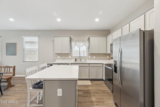 1281 W Highland Rd, San Tan Valley, AZ 85143 - kitchen with stainless steel appliances, wood finish floors, a breakfast bar area, a center island, and light countertops