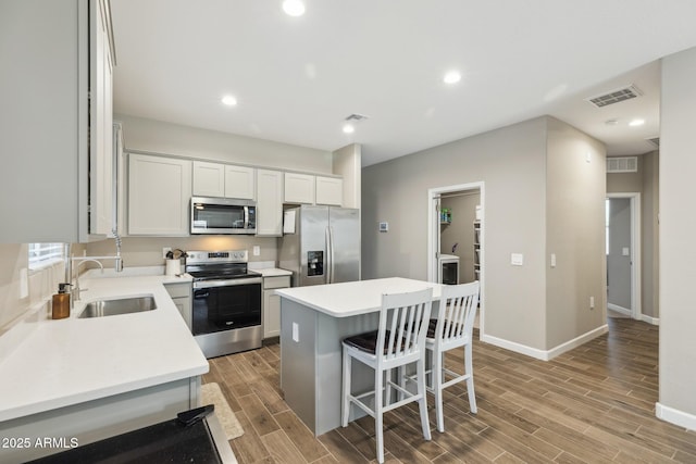 1281 W Highland Rd, San Tan Valley, AZ 85143 - kitchen featuring appliances with stainless steel finishes, a sink, a kitchen island, a breakfast bar area, and light wood-style floors