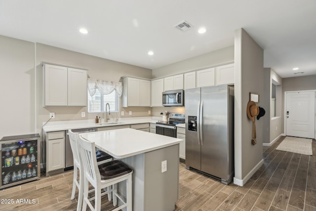 1281 W Highland Rd, San Tan Valley, AZ 85143 - kitchen featuring stainless steel appliances, wine cooler, a sink, wood finish floors, and light countertops
