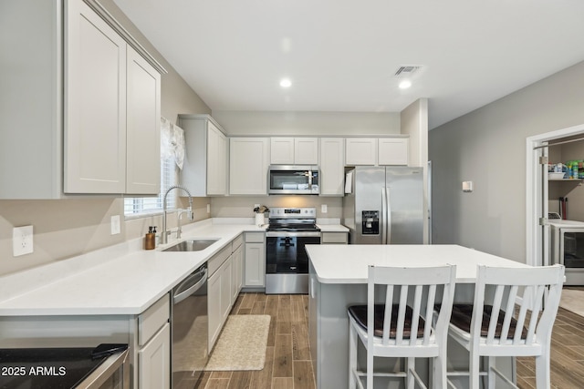 1281 W Highland Rd, San Tan Valley, AZ 85143 - kitchen featuring appliances with stainless steel finishes, a sink, wood finish floors, a kitchen bar, and a kitchen island