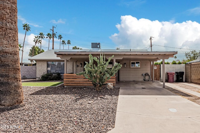 ranch-style home featuring a carport, brick siding, concrete driveway, and fence