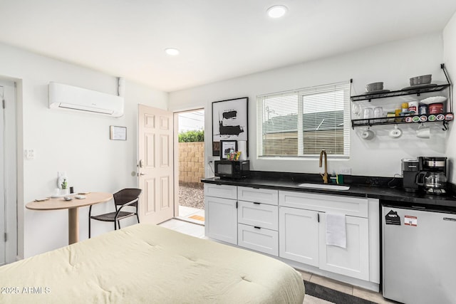 kitchen featuring white cabinets, dark countertops, freestanding refrigerator, a wall mounted air conditioner, and a sink