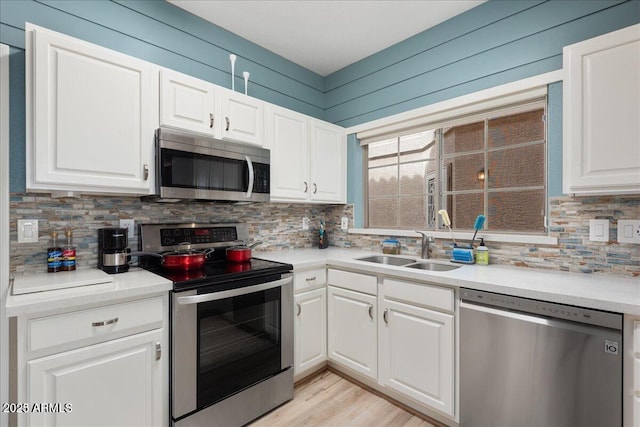 kitchen with white cabinetry, stainless steel appliances, sink, and tasteful backsplash