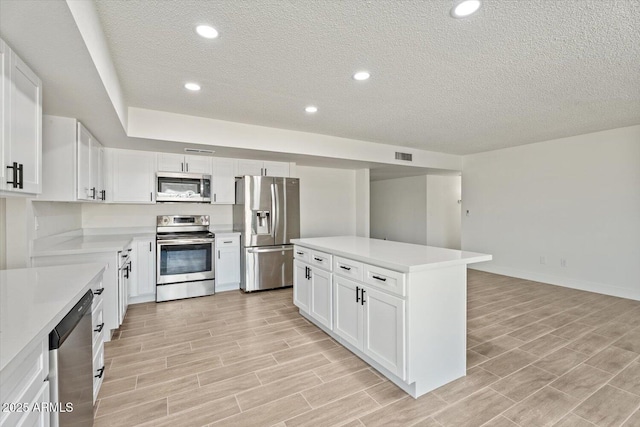 kitchen featuring appliances with stainless steel finishes, wood finish floors, light countertops, and a kitchen island