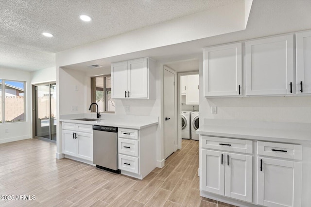 kitchen with washing machine and clothes dryer, light countertops, stainless steel dishwasher, white cabinetry, and a sink