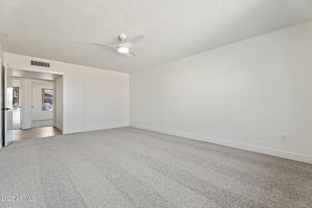 empty room featuring light carpet, ceiling fan, visible vents, and a textured ceiling