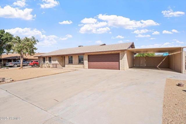 ranch-style house with driveway, an attached garage, an attached carport, and brick siding