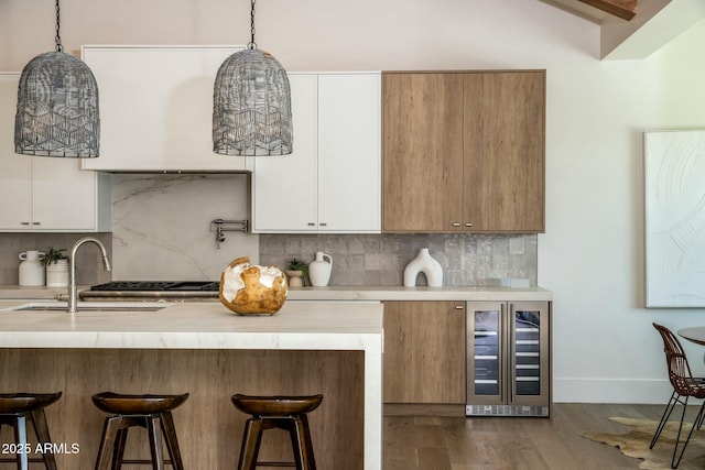 kitchen with white cabinetry, beverage cooler, sink, and pendant lighting