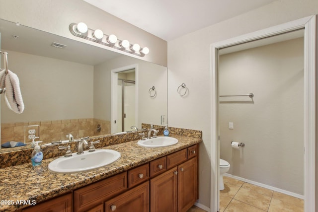 bathroom featuring tile patterned floors, a sink, toilet, and double vanity