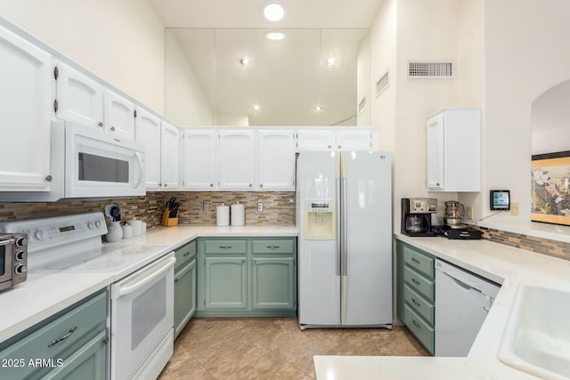 kitchen with tasteful backsplash, white appliances, sink, white cabinets, and light tile patterned flooring