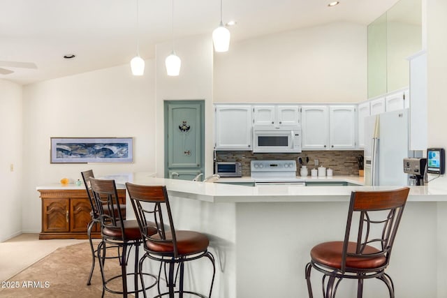 kitchen featuring tasteful backsplash, a breakfast bar, white appliances, high vaulted ceiling, and white cabinets