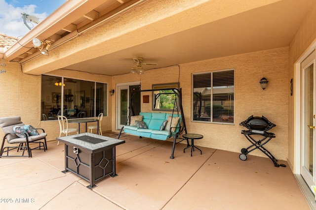 view of patio / terrace with ceiling fan and an outdoor living space with a fire pit