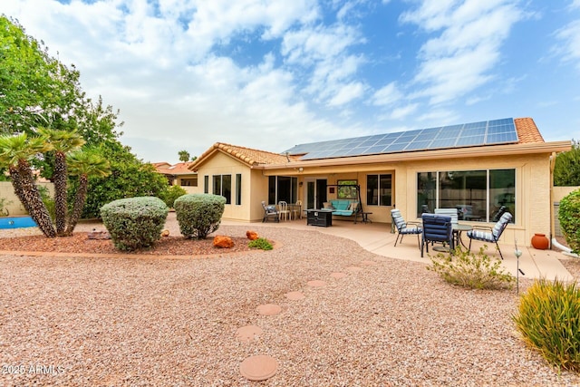 rear view of house with solar panels, an outdoor living space, and a patio