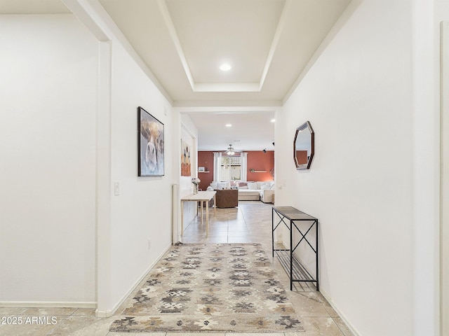 hallway featuring a raised ceiling and light tile patterned flooring