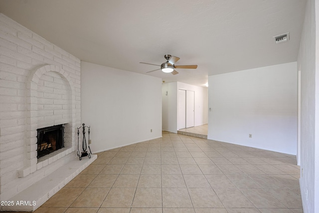 unfurnished living room with light tile patterned floors, visible vents, a fireplace, and a ceiling fan