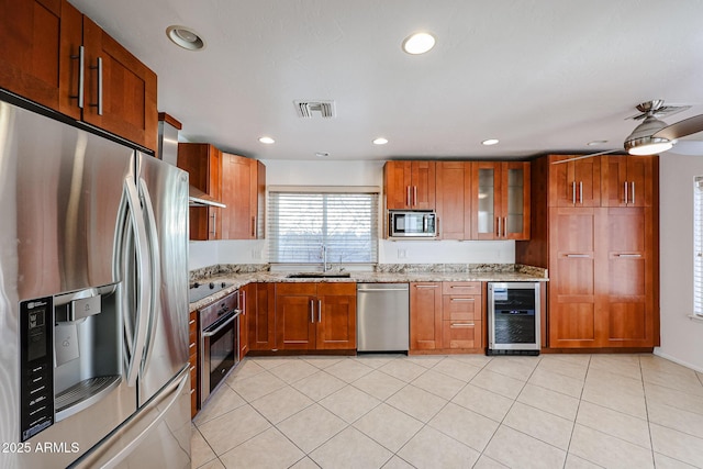 kitchen featuring a sink, stainless steel appliances, wine cooler, and light stone countertops