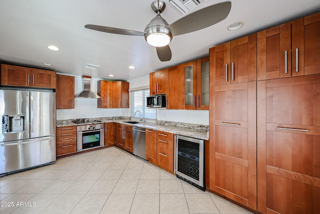 kitchen featuring beverage cooler, brown cabinetry, stainless steel appliances, and wall chimney exhaust hood