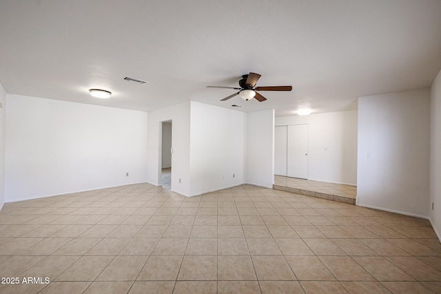 empty room with light tile patterned floors, a ceiling fan, and visible vents