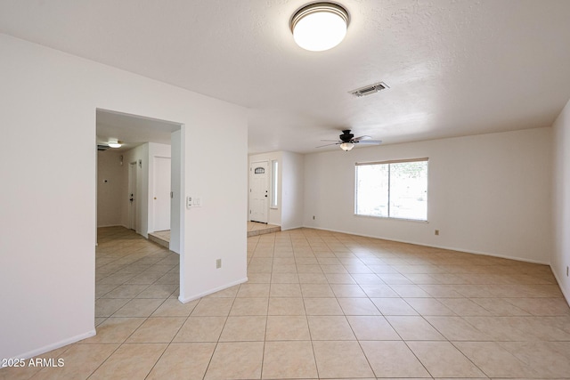 unfurnished room featuring a textured ceiling, light tile patterned floors, visible vents, and ceiling fan