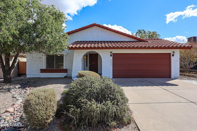 mediterranean / spanish home with stucco siding, driveway, an attached garage, and a tiled roof