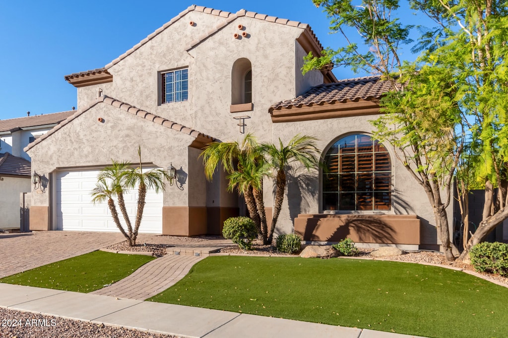 mediterranean / spanish-style house with a garage and a front lawn