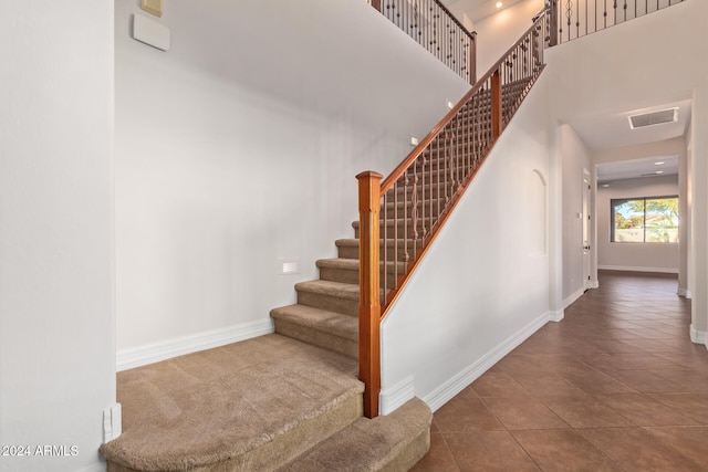 staircase featuring tile patterned floors and a high ceiling