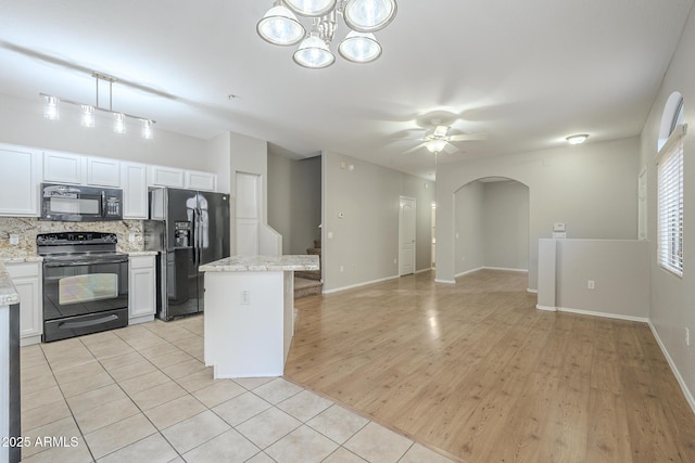 kitchen featuring black appliances, ceiling fan with notable chandelier, white cabinetry, and backsplash