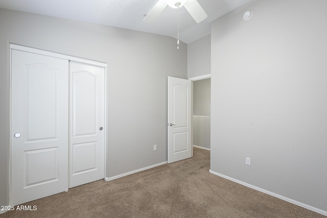 unfurnished bedroom with ceiling fan, a closet, light carpet, and lofted ceiling