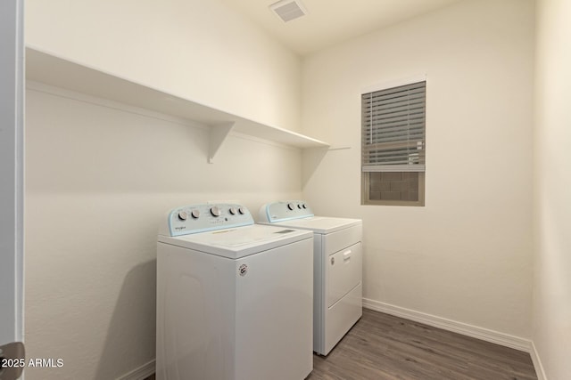 clothes washing area with wood-type flooring and separate washer and dryer