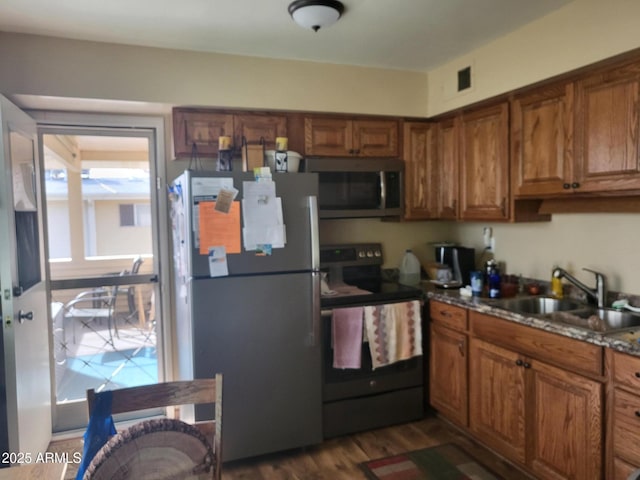 kitchen featuring light stone countertops, appliances with stainless steel finishes, sink, and dark wood-type flooring